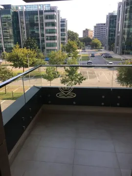 Balcony with a glass railing and a view of surrounding buildings and parking. - image 9