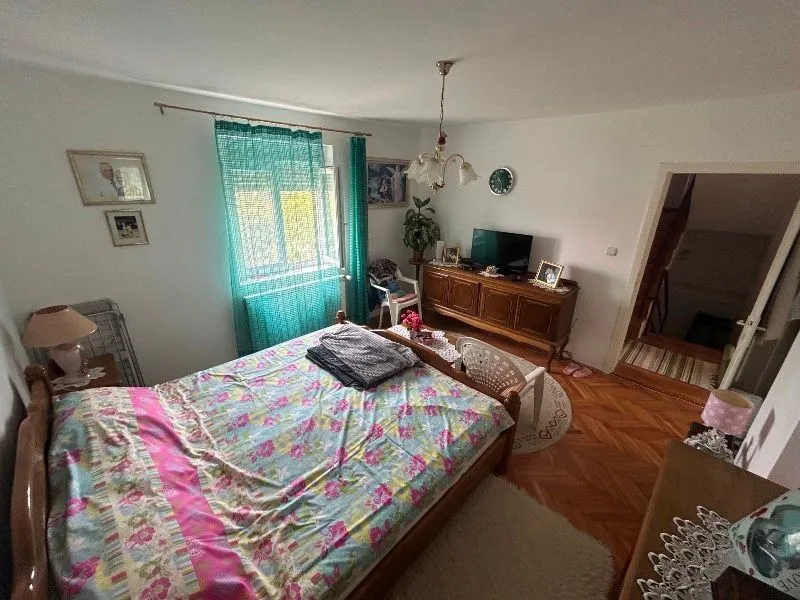 Furnished bedroom with a double bed, wooden dresser, and a window.