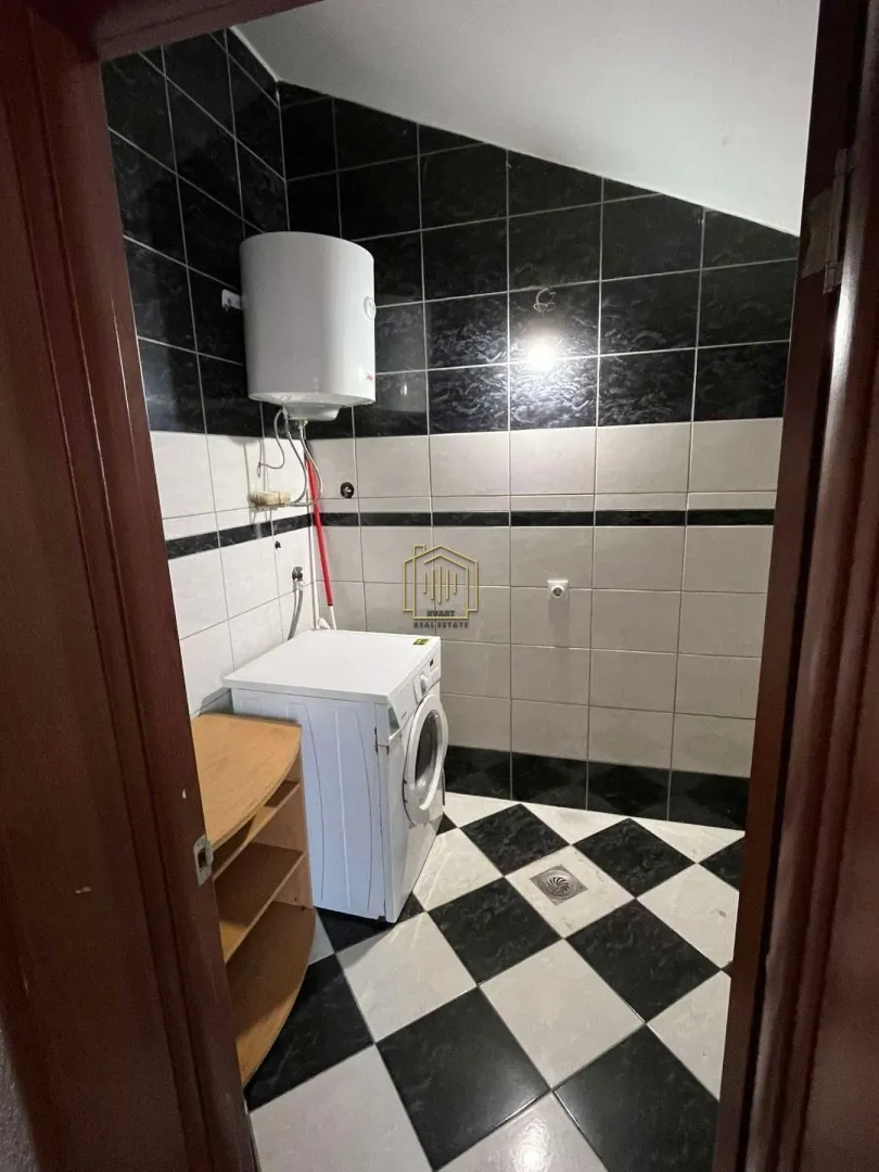 Manje kupatilo sa tuš-kabinom, pločicama i veš-mašinom.