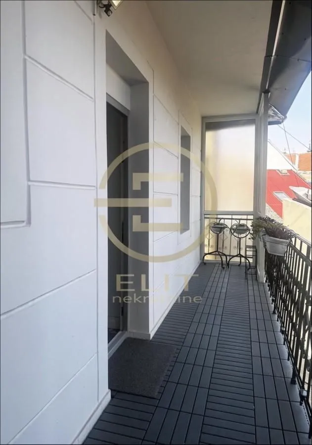 Natkriveni balkon sa podom od tamnih dasaka i metalnom ogradom.