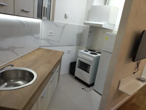 Small kitchen with a wooden countertop and built-in appliances. - image 8
