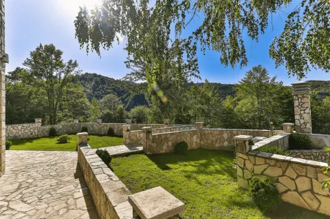 Pogled na uređeno dvorište sa kamenim ogradama i zelenilom. - image 7