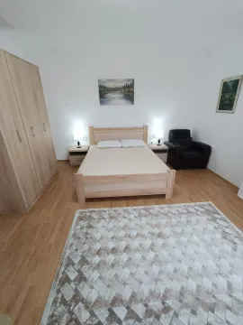Svijetla spavaća soba sa drvenim bračnim krevetom, ormarom i foteljom. - image 7