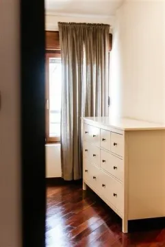 Bright room corner featuring a wooden dresser next to a window with parquet flooring. - image 18