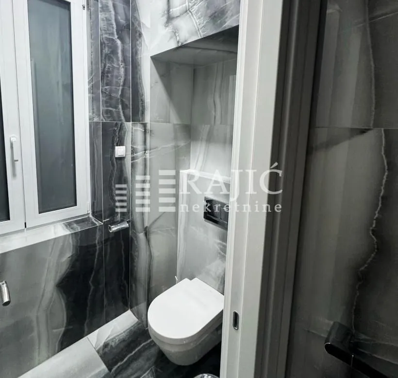 Modernly equipped bathroom with marble tiles.