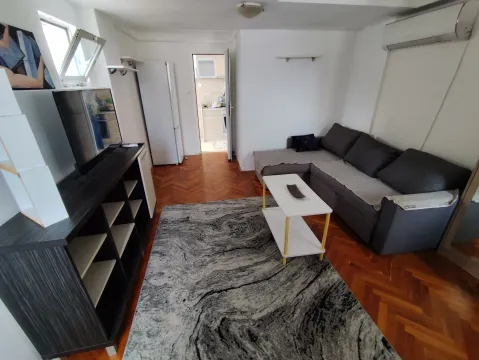 Living room with a sofa, TV, and a view into the kitchen. - image 2
