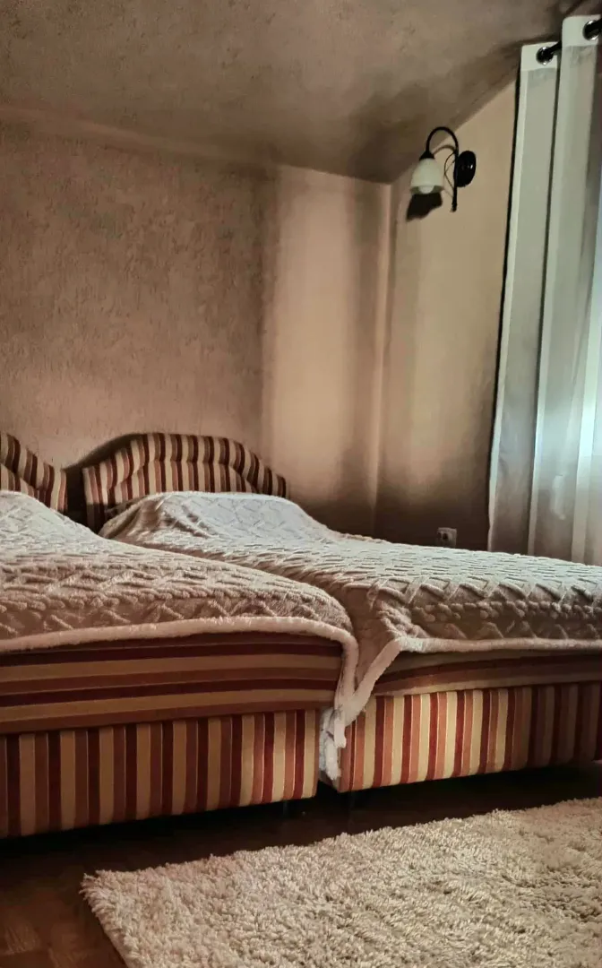 Bedroom with two single beds and a wall lamp.