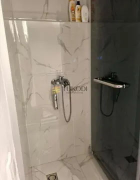 Walk-in shower enclosure with marble-look tiles and modern fixtures. - image 7