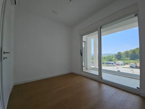 Prazna soba sa parketom i velikim staklenim vratima koja vode na terasu. - image 10