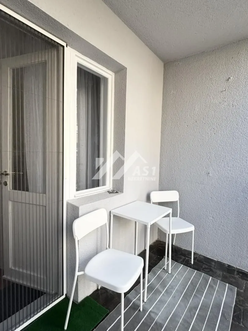 Manji natkriveni balkon sa garniturom za sedenje i izlazom u stan.