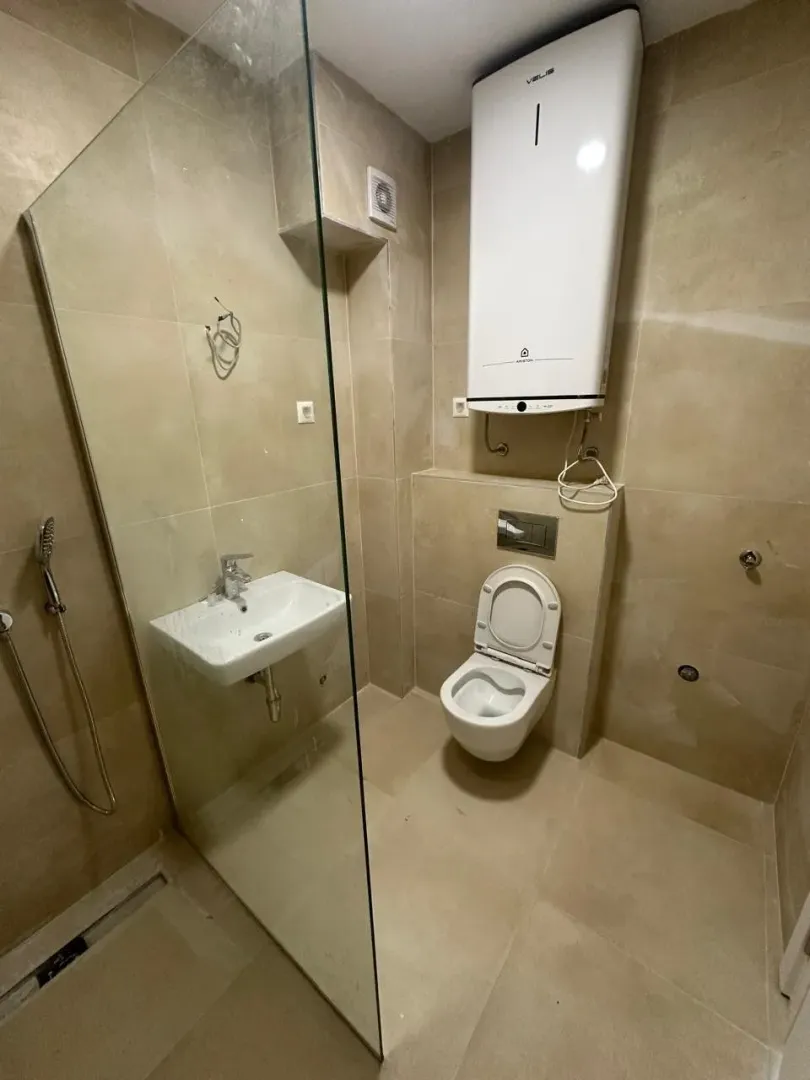 Kupatilo obloženo keramičkim pločicama sa tuš kabinom, umivaonikom, toaletom i bojlerom.