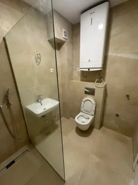 Kupatilo obloženo keramičkim pločicama sa tuš kabinom, umivaonikom, toaletom i bojlerom. - image 3