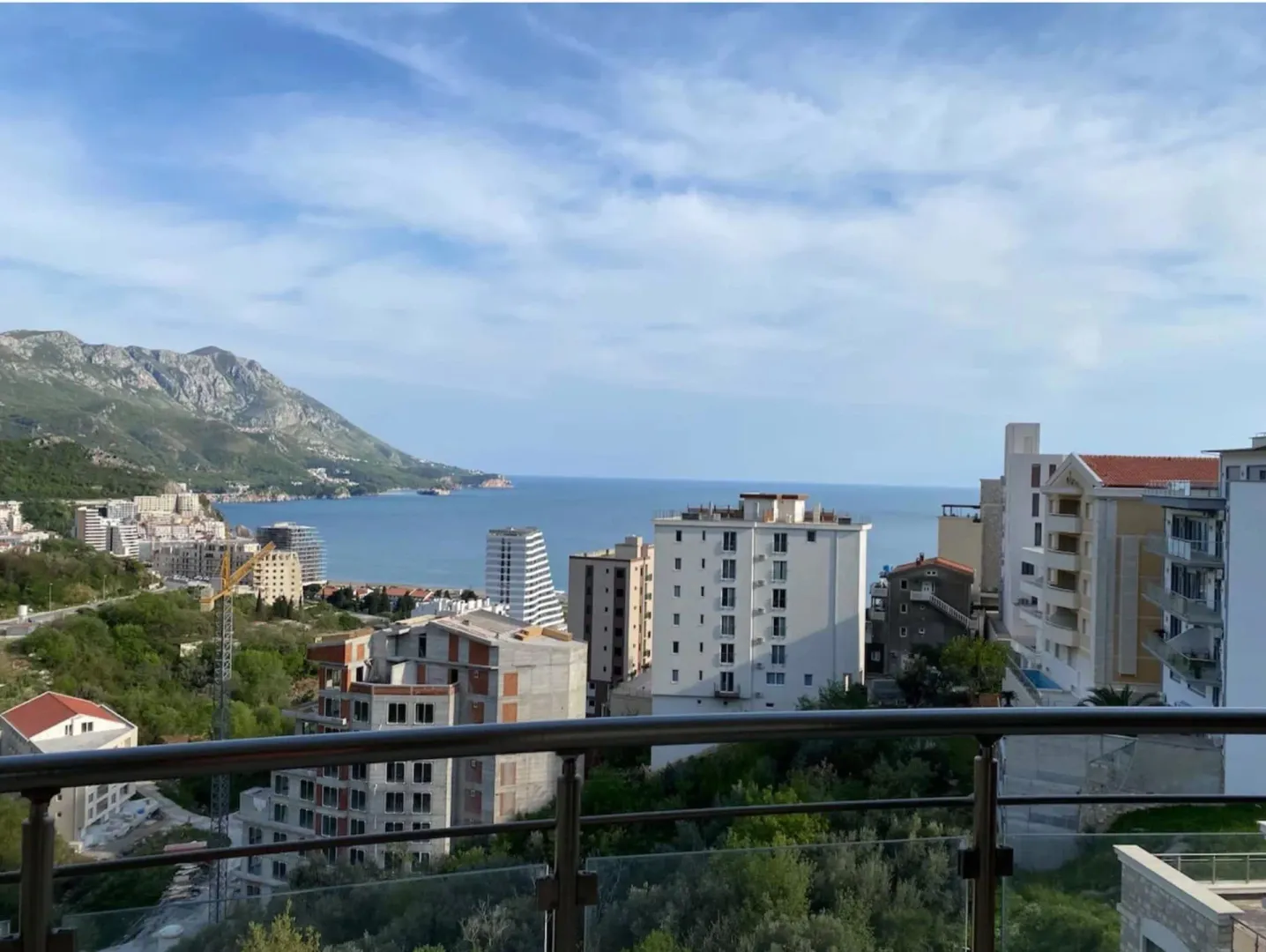 Pogled sa terase na more, planine i okolne zgrade.