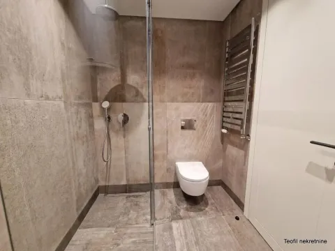 Moderno kupatilo sa tuš kabinom obloženom staklom i ugradnom šoljom. - image 2