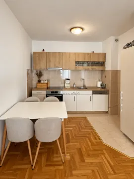 Kitchen with wooden units and a dining table with four chairs. - image 3