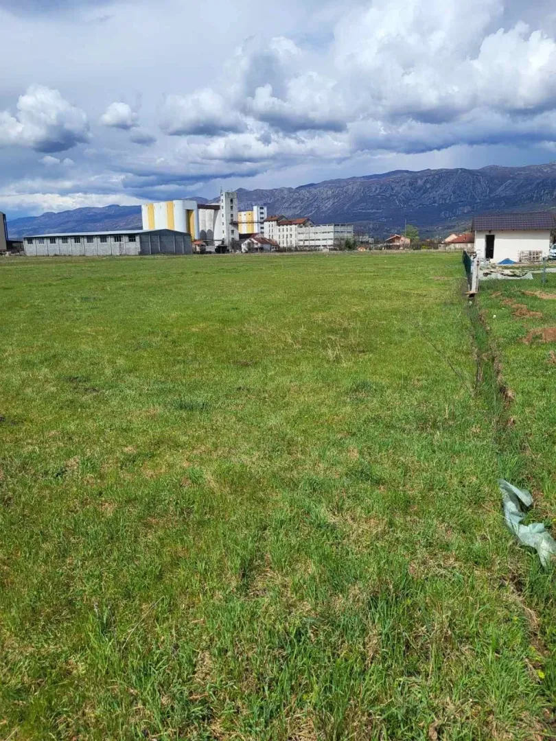 Prostrani zeleni plac sa pogledom na planine u pozadini.