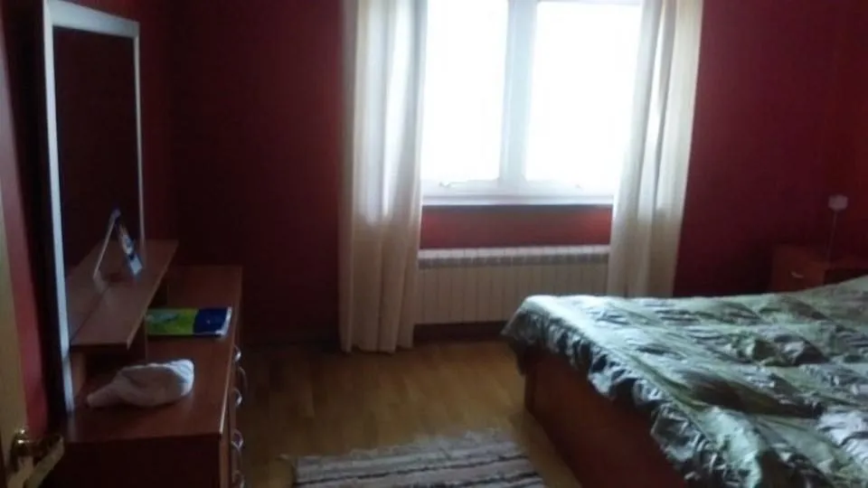 Spavaća soba sa crvenim zidovima, bračnim krevetom i prozorom.