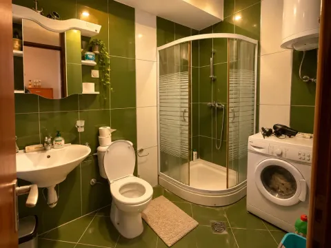 Bathroom with a shower cabin, sink, toilet, and washing machine. - image 5