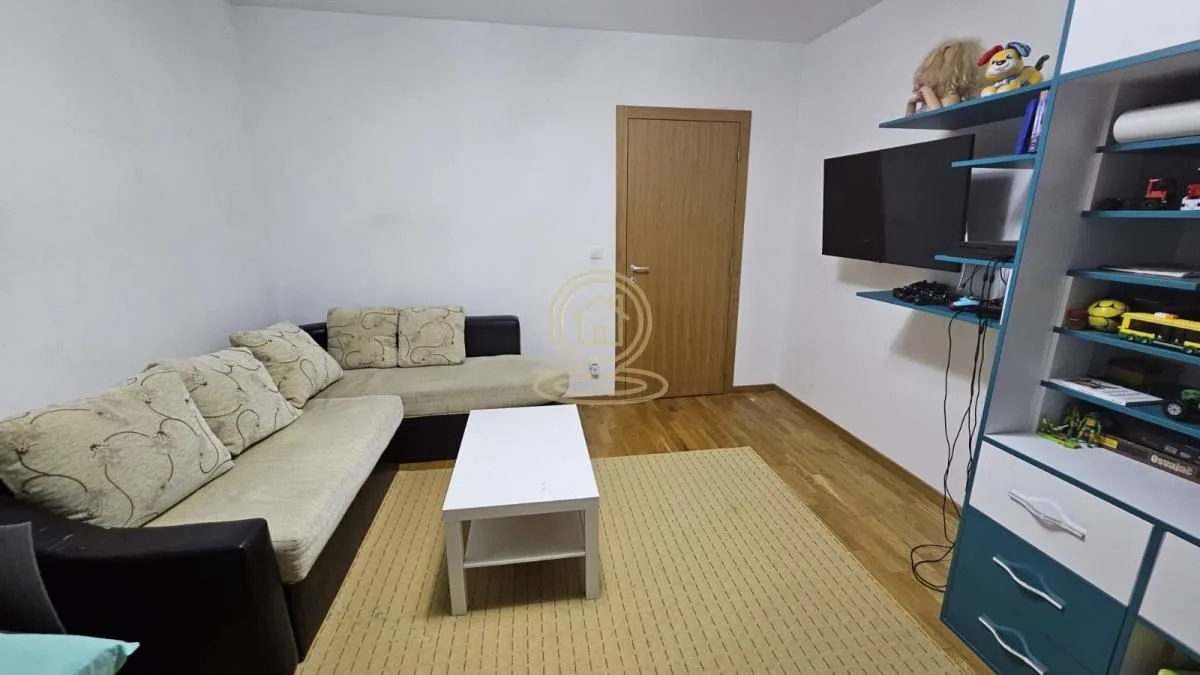 Living room with a corner sofa, coffee table, and a TV shelf unit.