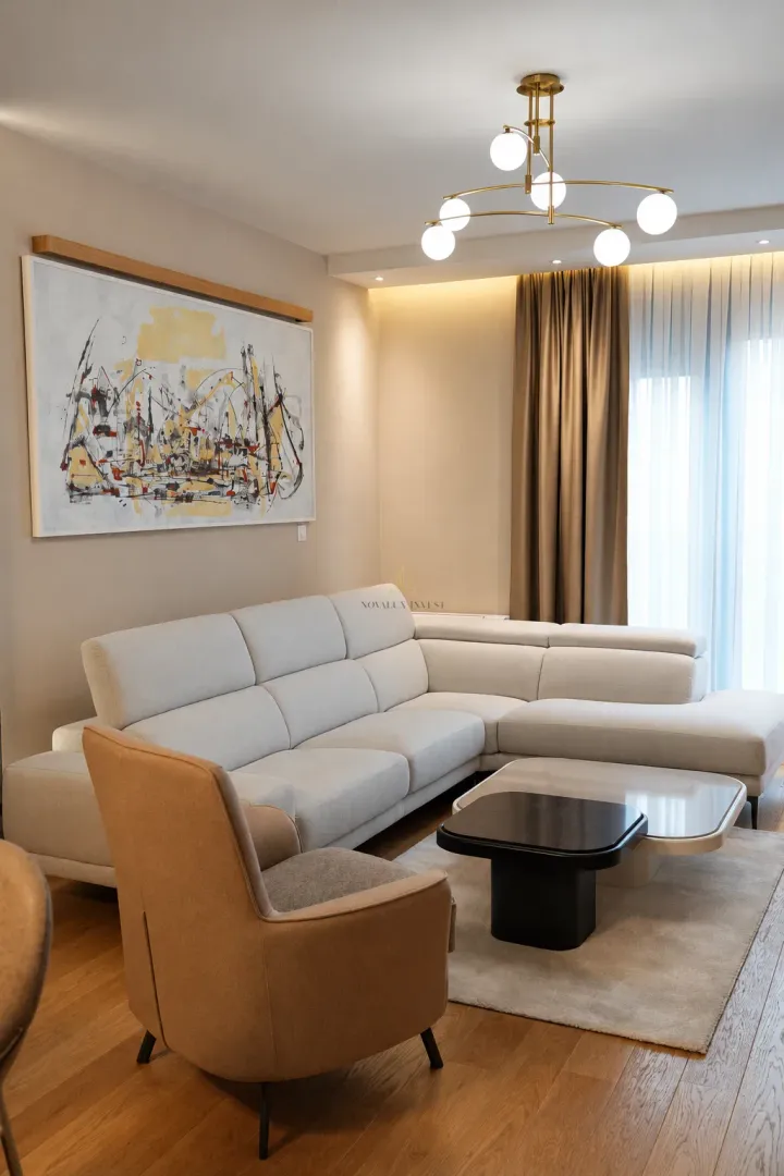 Living room with a sectional sofa, armchair, and modern chandelier.