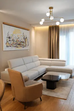Living room with a sectional sofa, armchair, and modern chandelier. - image 3