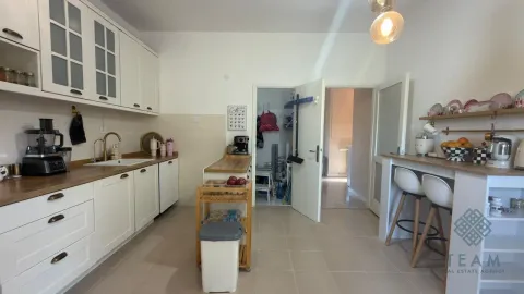 Bijela kuhinja sa drvenim radnim površinama, ostrvom i šankom za sjedenje. - image 16