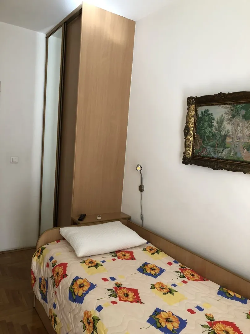 A simply furnished bedroom featuring a single bed and a wooden wardrobe.