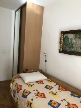 A simply furnished bedroom featuring a single bed and a wooden wardrobe. - image 13