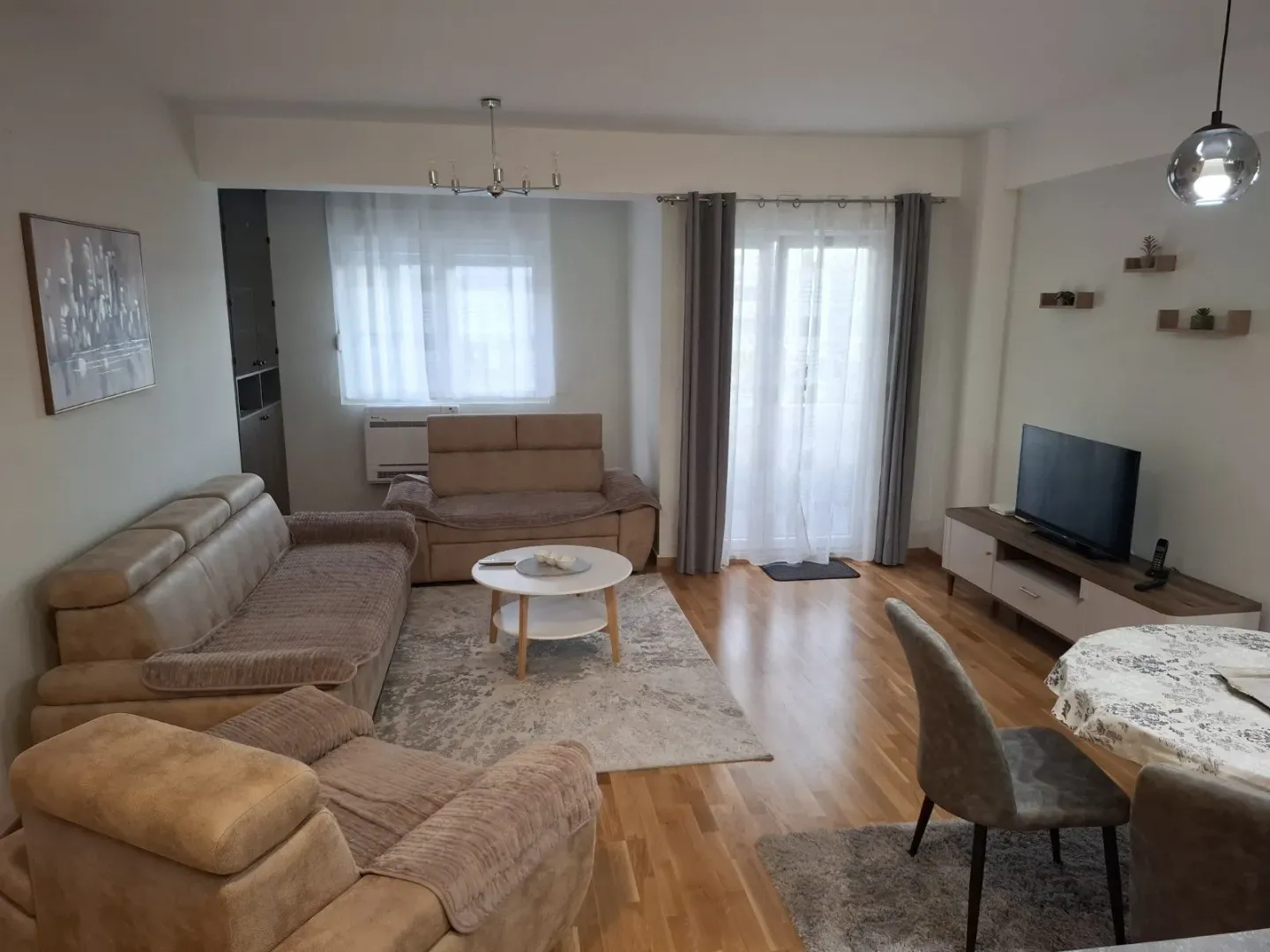 Prostrana dnevna soba sa garniturom za sedenje, stočićem i TV komodom.