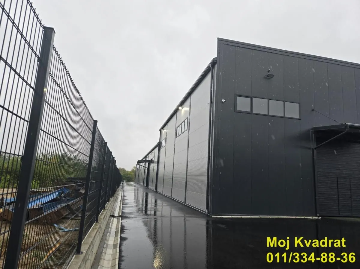 Exterior view of the industrial building with a metal fence and paved yard.