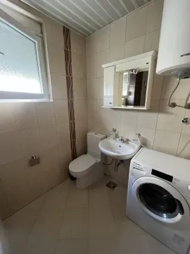 Smaller bathroom with a sink, toilet, washing machine, and a mirror. - image 9