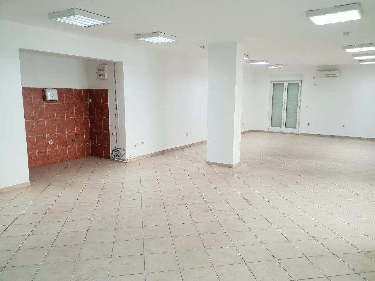 Spacious and bright empty commercial space with tiled flooring.