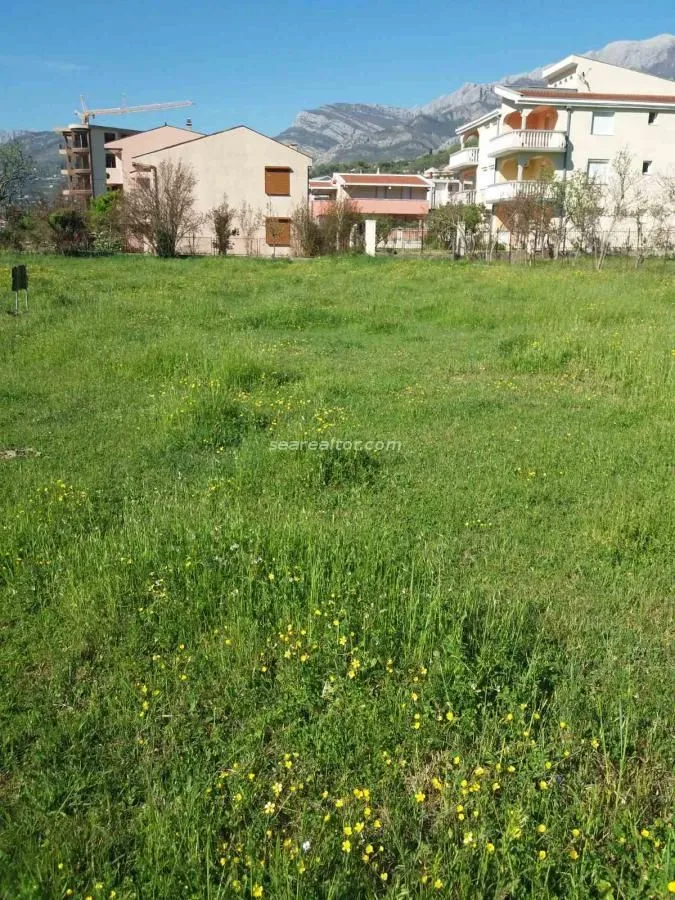 Zelena parcela sa pogledom na okolne zgrade i planine.