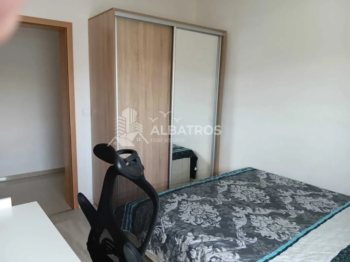 Furnished bedroom with a bed, a large wardrobe, and an office chair.