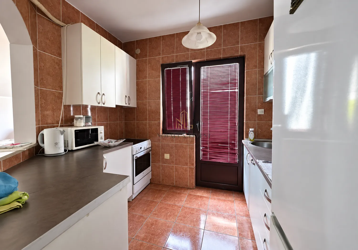 Kitchen equipped with white cabinets, a stove, and access to the terrace.