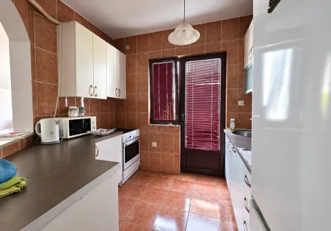 Kitchen equipped with white cabinets, a stove, and access to the terrace. - image 6