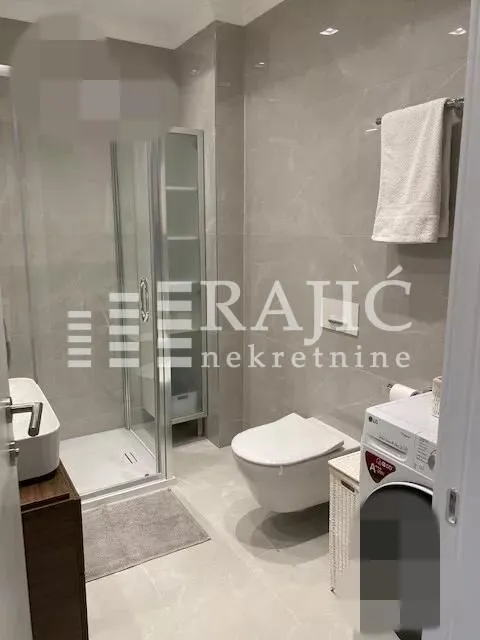 Modern bathroom with a walk-in shower and washing machine.