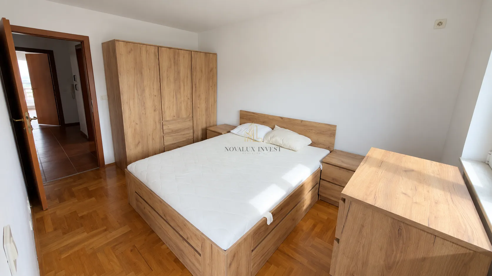 Furnished bedroom with a double bed and wooden wardrobe.