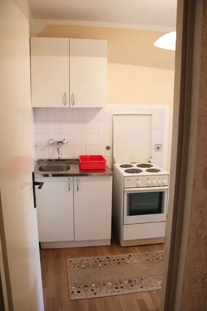 Manja kuhinja sa belim elementima, sudoperom i šporetom.
