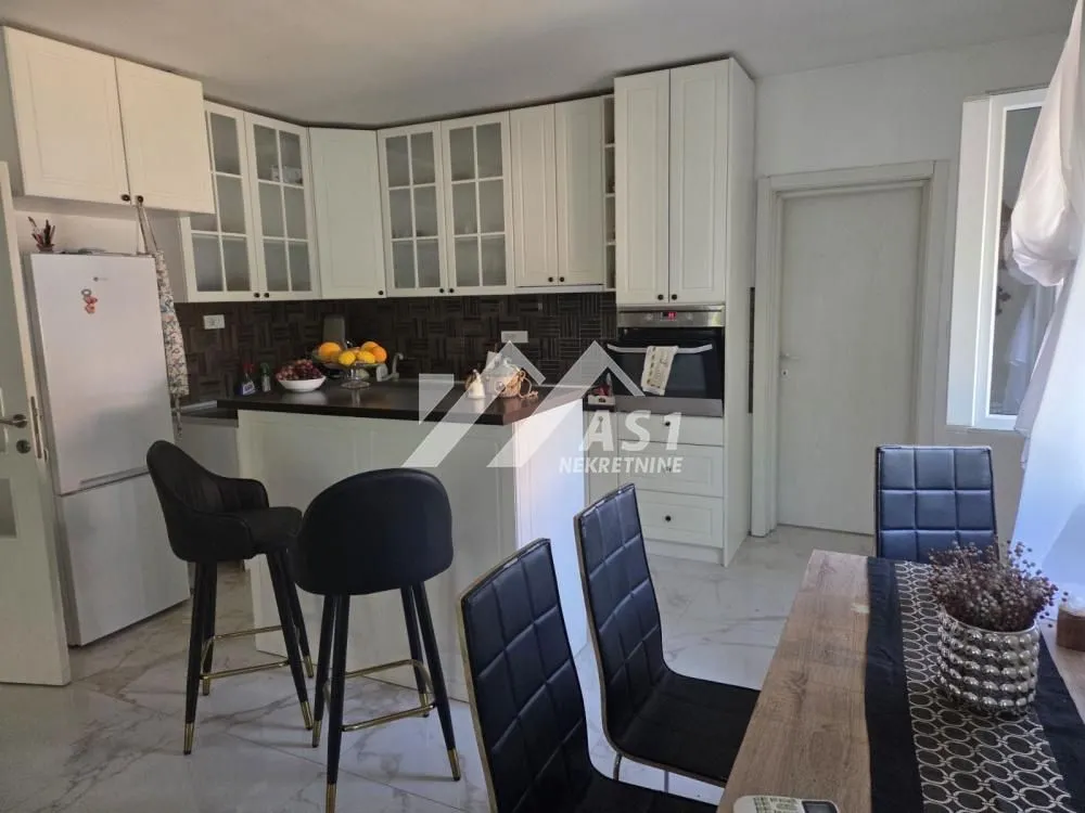 Kitchen with white cabinetry, a breakfast bar, and a dining area.