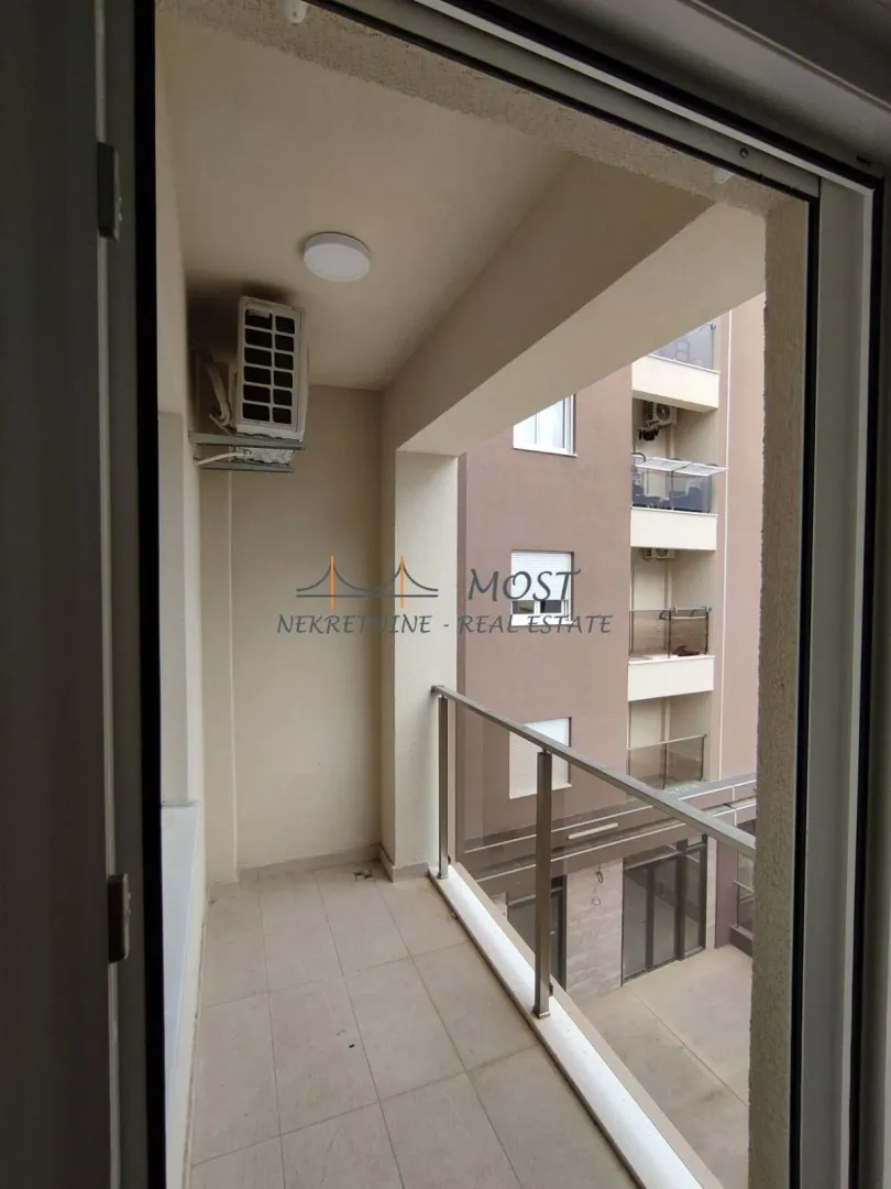 A view of a spacious enclosed balcony with a glass railing.