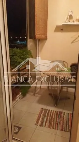 Manji namesteni balkon sa stolom i stolicama noću.