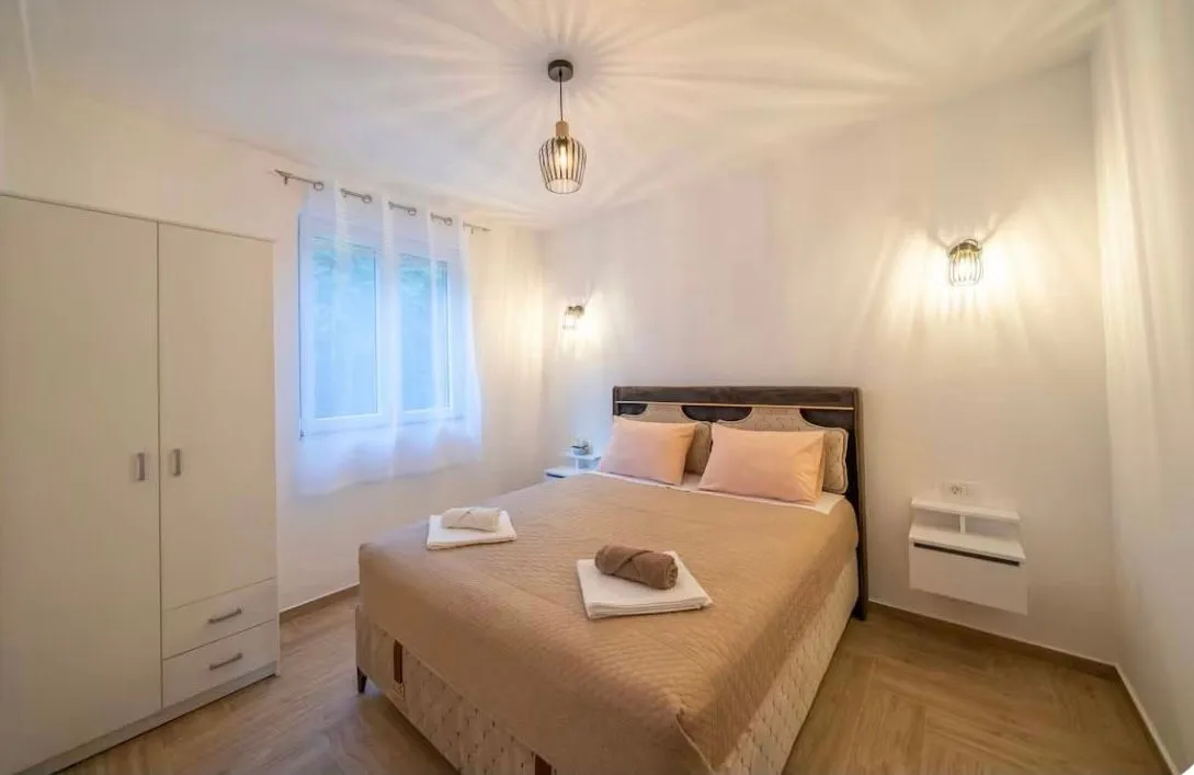 Furnished bedroom with a double bed, wardrobe, and window.
