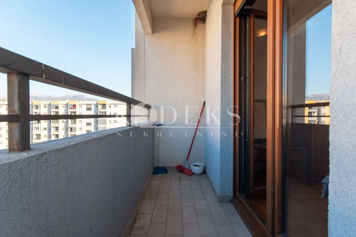 Covered balcony with a metal railing and a view of the neighborhood.