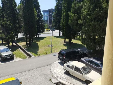 View from the terrace towards the surrounding greenery and parking in front of the building. - image 16