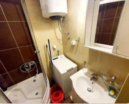 Smaller bathroom with a shower cabin, washbasin, and washing machine. - image 7