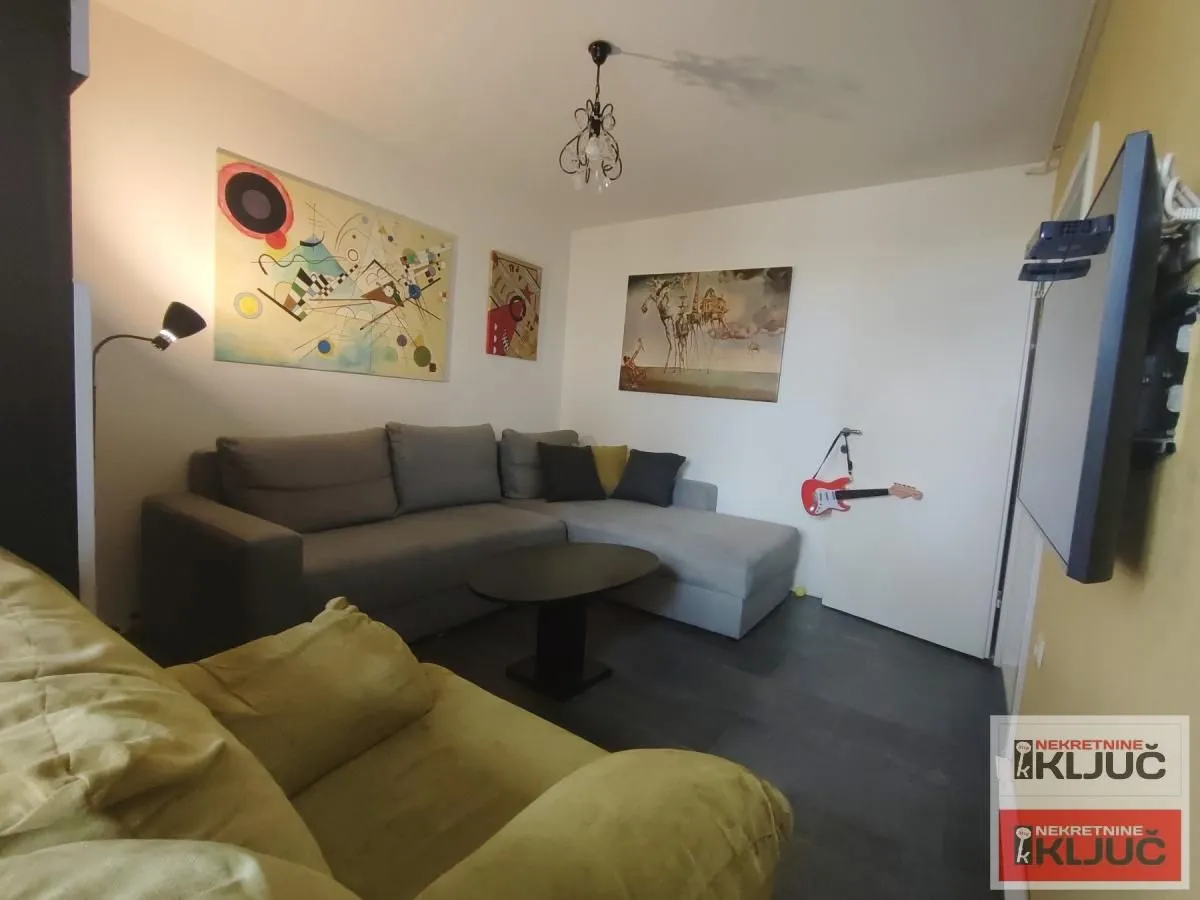 Dnevna soba sa garniturom za sedenje i slikama na zidu.