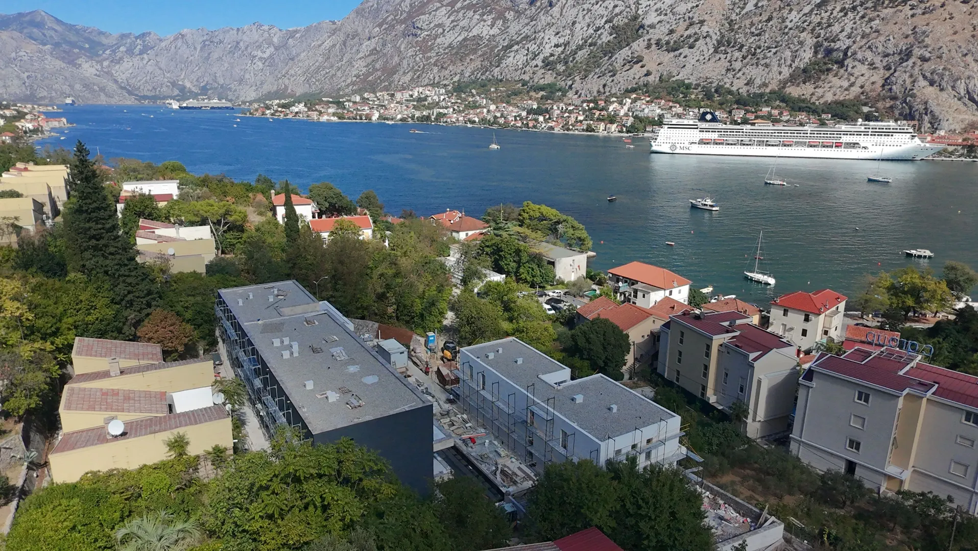 Pogled iz vazduha na zaliv, planine i okolne objekte sa brodom na vodi.