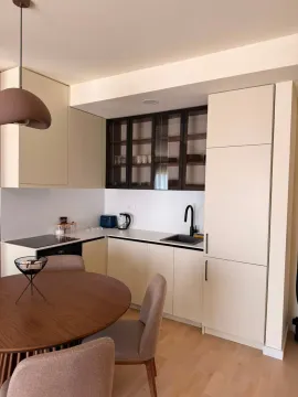 Modern kitchen with white cabinetry and a dining table with chairs. - image 8