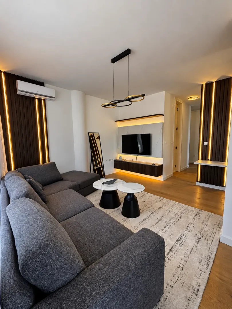 Modern living room with a sectional sofa, TV, and decorative lighting.